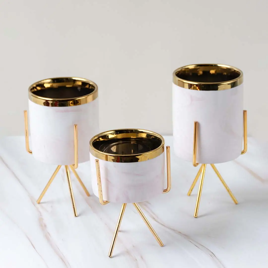 Decorative white marble finish planter pot set with gold metal stands for modern indoor plant styling and decor.