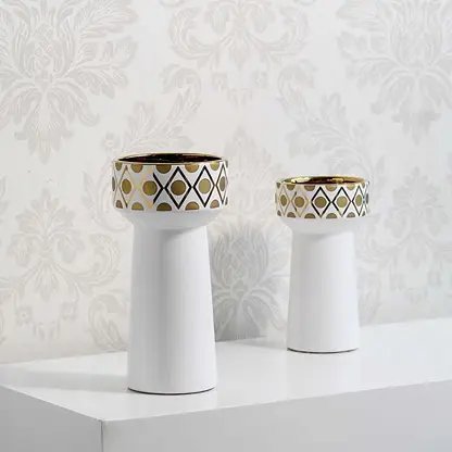 A stylish white and gold decorative vase displayed in a grouped setting highlighting its modern shape and refined detailing for home styling.