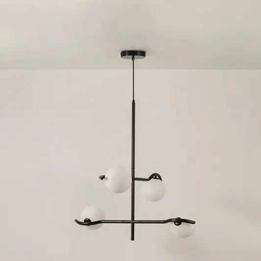Black metal chandelier with white globes shown on a bright white background with lights off for a sleek minimal modern look.