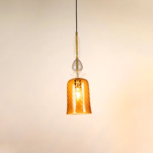 Amber glass pendant light illuminated to display elegant hanging light design with warm decorative lighting effects.