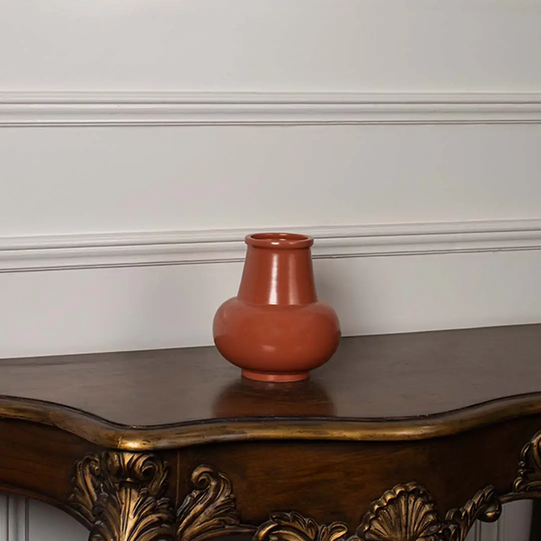 Minimal white background view of the orange ceramic vase showcasing its glossy surface and contemporary rounded design.