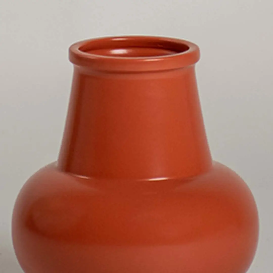 Closeup view of the orange ceramic vase showing its smooth glossy finish and modern rounded silhouette for stylish home decor.