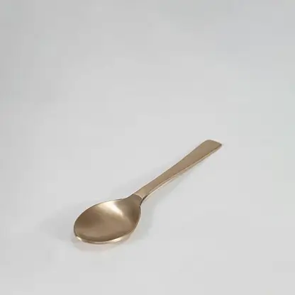 Brass spoon with curved bowl and simple flat handle design shown on plain white background for utensil detail.