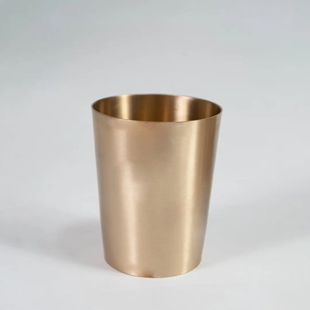 A brass cup shown on a white background highlighting its smooth metallic finish and simple cylindrical shape designed for everyday serving use.
