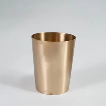 A brass cup shown on a white background highlighting its smooth metallic finish and simple cylindrical shape designed for everyday serving use.