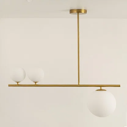 Gold linear chandelier displayed with lights off showing sleek frame frosted glass globes and modern minimalistic aesthetic design.