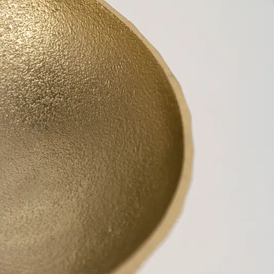 Closeup metal decor bowl in gold finish with textured surface for table decor or shelf styling modern home placement white background.