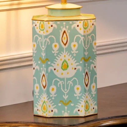 Table lamp closeup showing teal ceramic base with hand painted ikat pattern and gold trimmed edges.