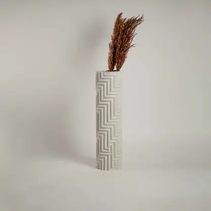 White ceramic vase with geometric detailing against a clean white backdrop emphasizing its refined craftsmanship.