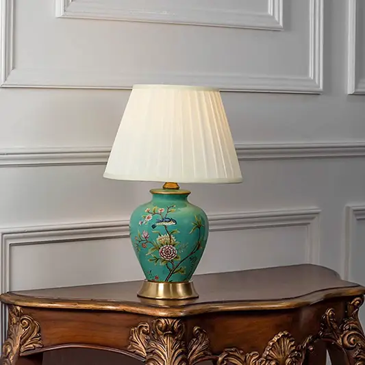 Table lamp with green ceramic base and white pleated shade on wooden console table classic decorative lighting for living room decor.