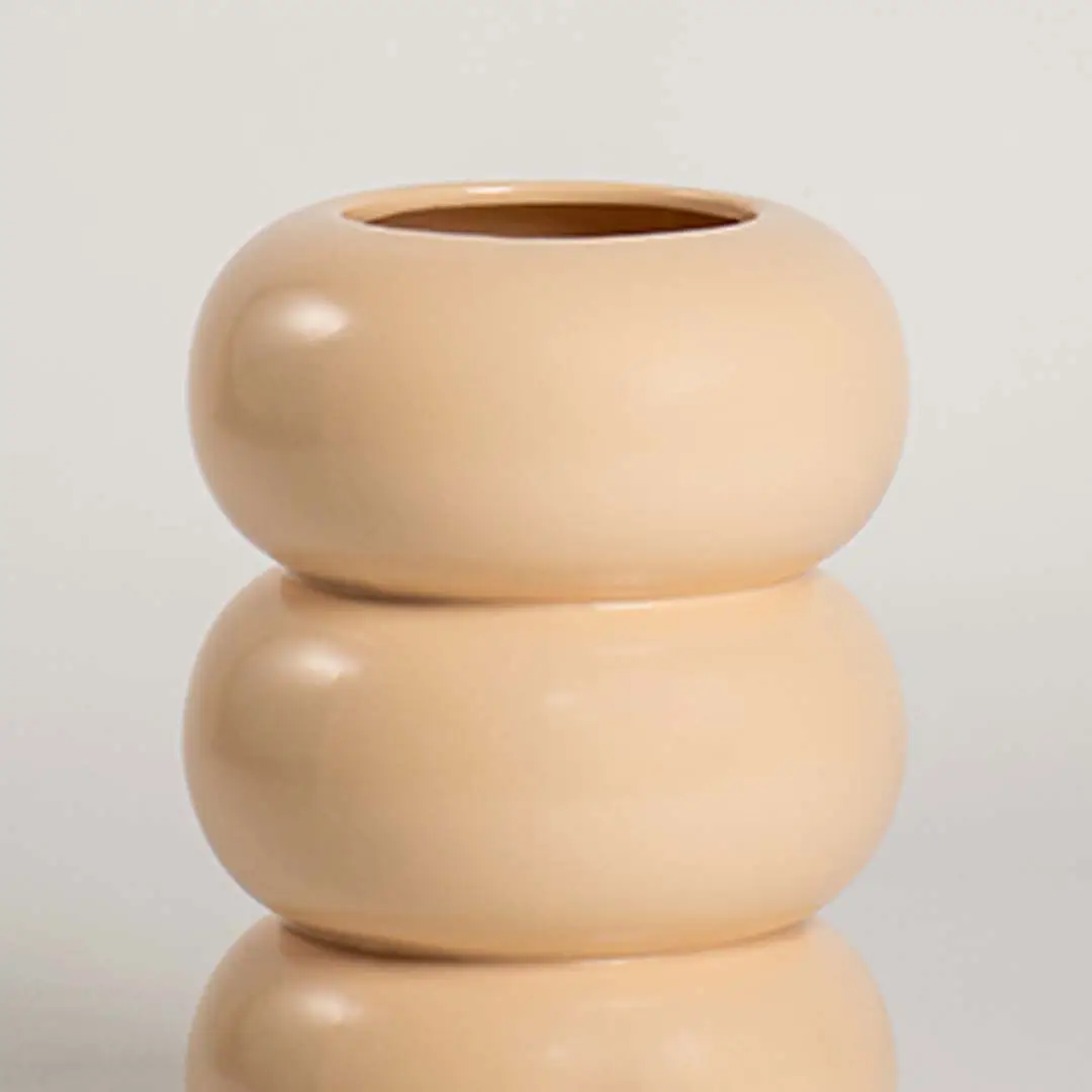 Closeup image of a soft peach cream ceramic vase showing its smooth three ring stacked bubble shape and texture.