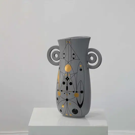 Grey ceramic vase with abstract gold and black detailing and loop handles displayed on a clean white background for modern decor styling.