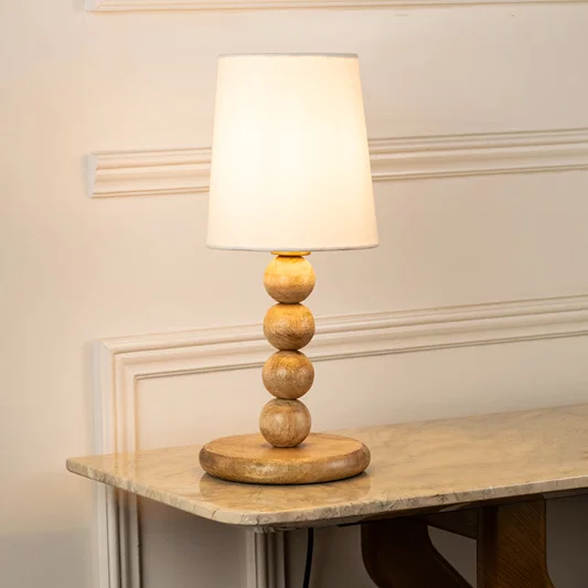 Closeup of table lamp with white fabric shade and sculpted base showcasing elegant design and warm lighting for bedroom decor styling.