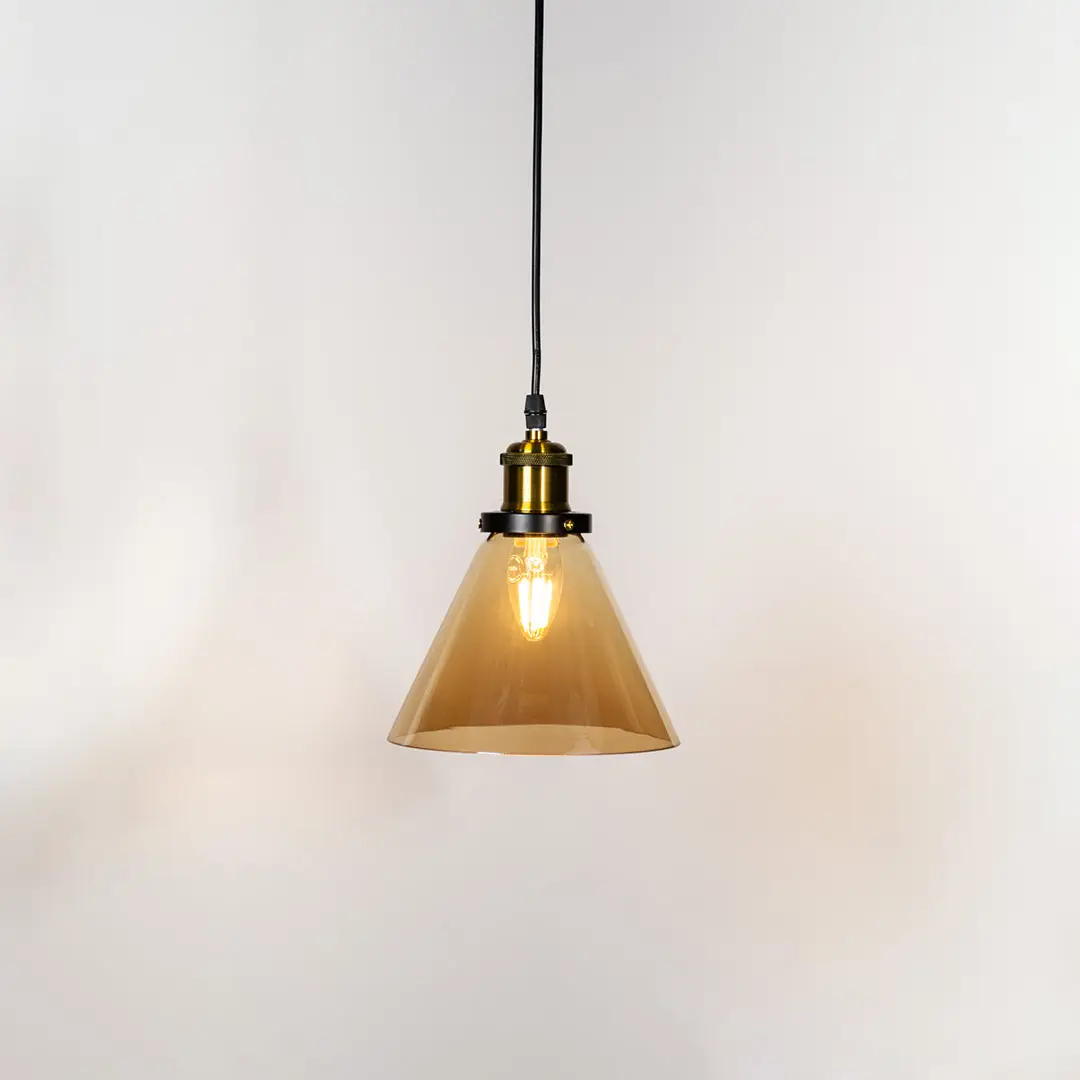 Amber glass cone pendant light illuminated with warm glow and brass metal accents for stylish ceiling lighting decor.
