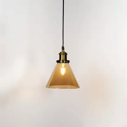 Amber glass cone pendant light illuminated with warm glow and brass metal accents for stylish ceiling lighting decor.