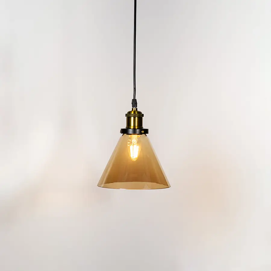 Amber glass cone pendant light illuminated with warm glow and brass metal accents for stylish ceiling lighting decor.
