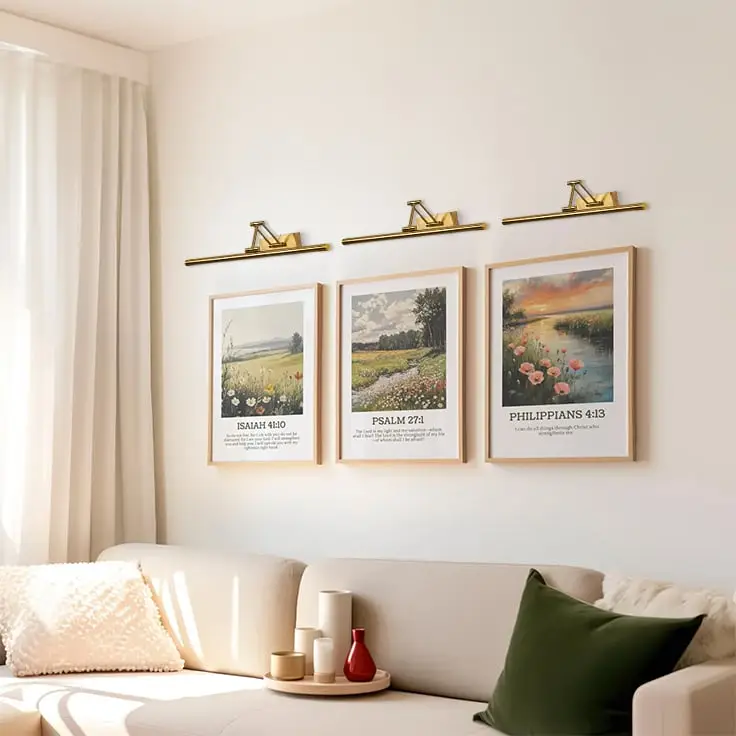 Gold picture light enhancing artwork in a modern interior bringing warm focused lighting to living room and hallway wall decor.