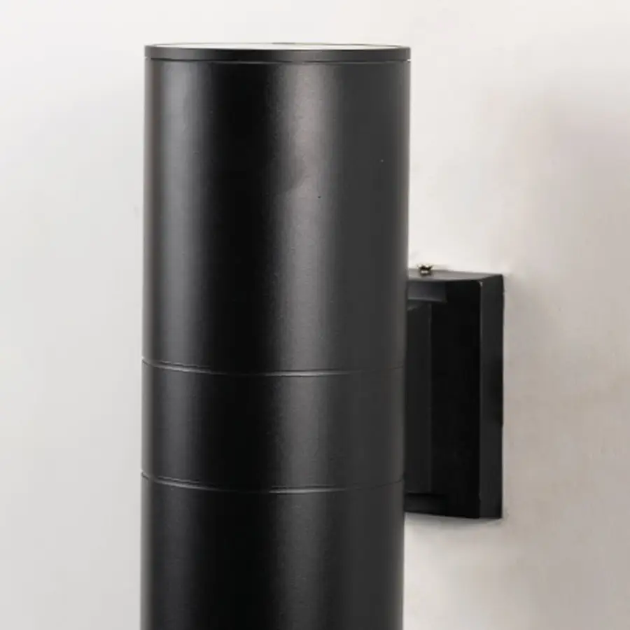 Closeup of tall black metal cylindrical outdoor wall light showing smooth matte finish and modern exterior design.