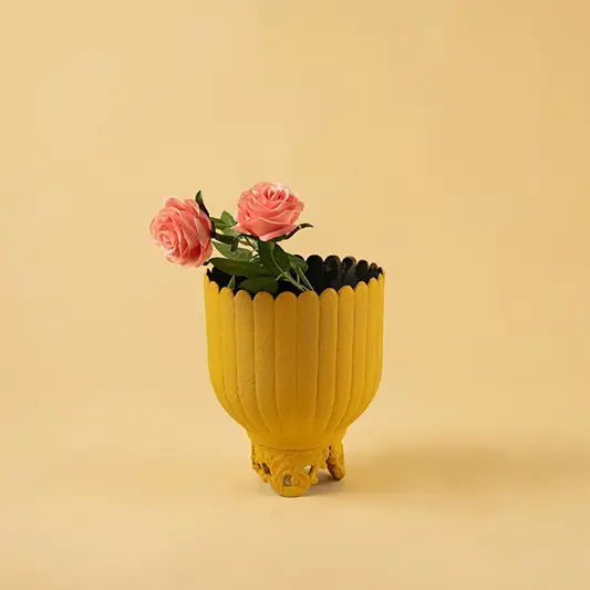 Vibrant ribbed yellow metal planter with pink flowers for modern home decor and cheerful interior styling.
