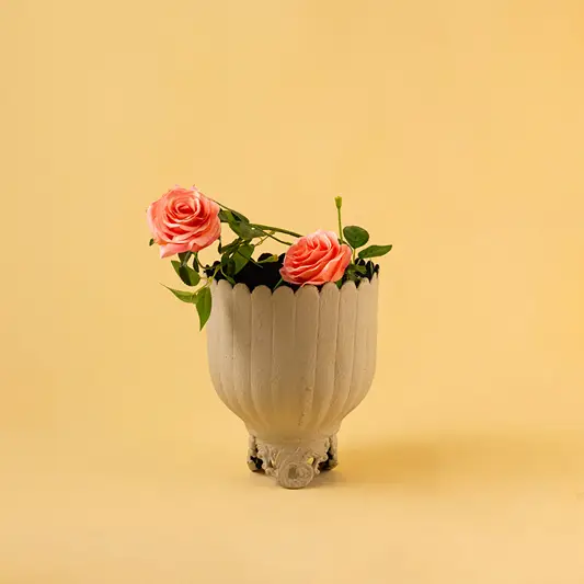 Ribbed light grey metal planter with pink flowers for modern home decor and stylish tabletop accent display.
