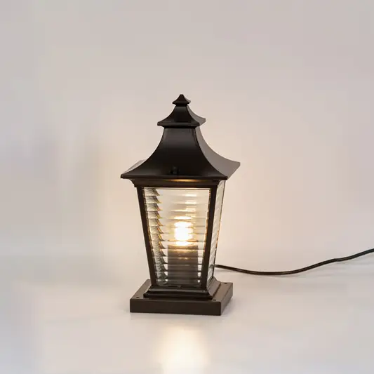 Vintage black outdoor gate light with warm glowing ribbed panels for stylish exterior decor use.