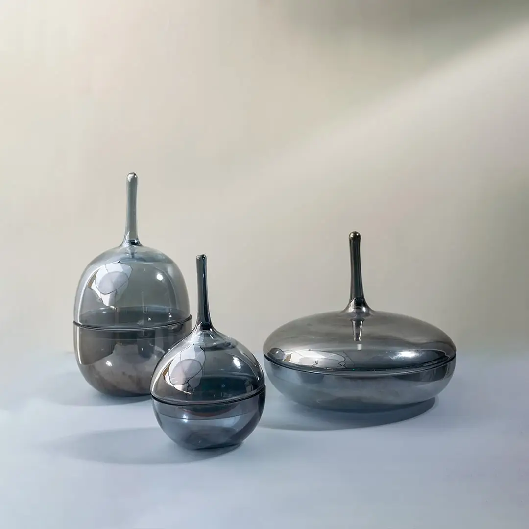 Set of glossy grey glass jars in different sizes styled together as modern decorative accents for chic interiors.