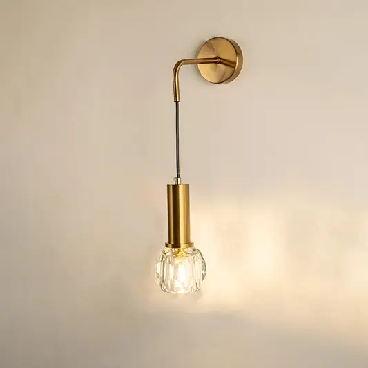 Gold metal wall light with hanging bulb design emitting warm glow ideal for bedroom or hallway wall decor placement.
