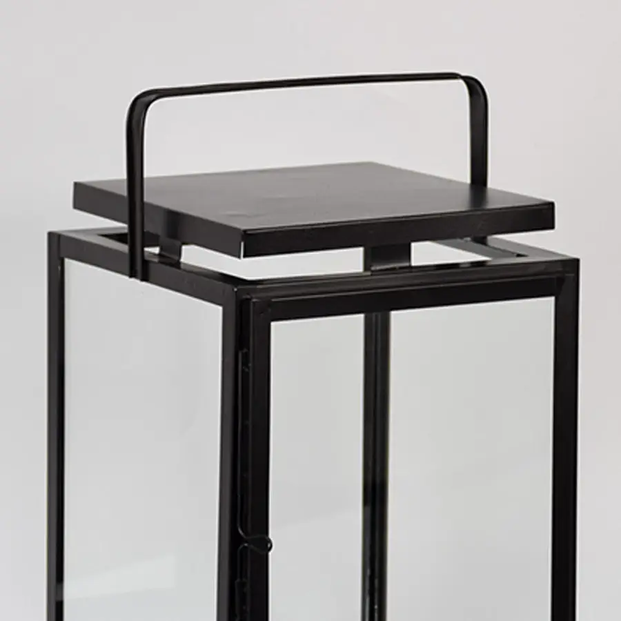 Closeup of black metal lantern with flat top handle for modern indoor decor styling use.