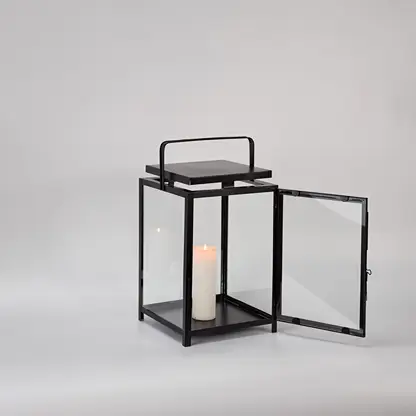 Black metal lantern with open glass door and candle holder for elegant tabletop decor styling.