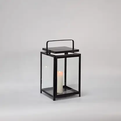 Black metal lantern with clear glass panels and candle holder for modern tabletop decor styling.