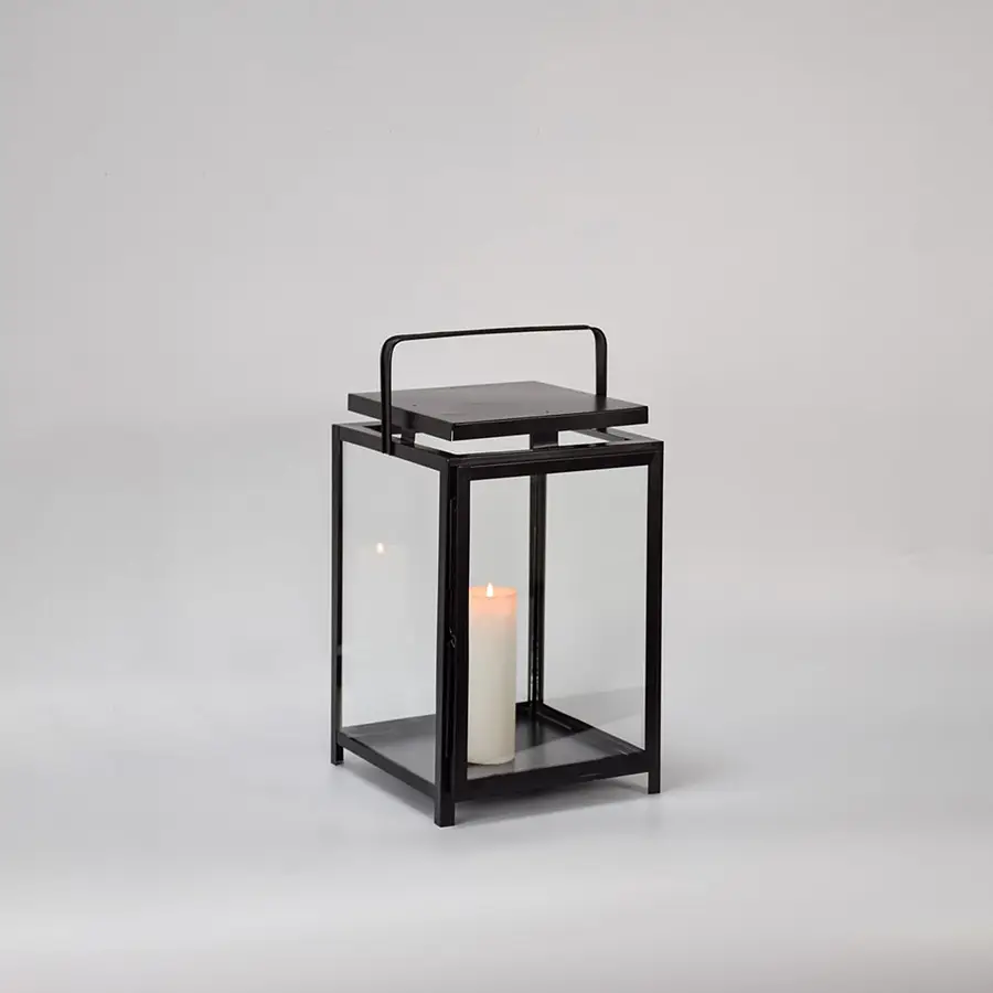 Black metal lantern with clear glass panels and candle holder for modern tabletop decor styling.