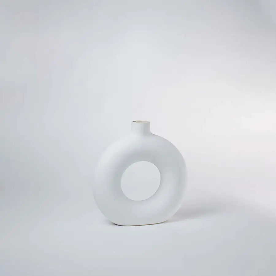 Minimal white ceramic vase with circular hollow design perfect for modern shelf or table decor placement on clean white background.