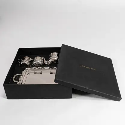 Complete silver tea set displayed on white background highlighting intricate engravings and polished metallic shine.
