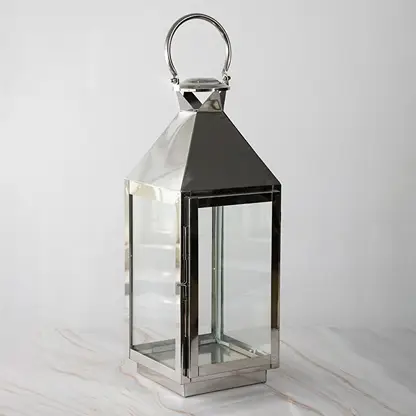 Tall stainless steel lantern turned off shown plain on white background highlighting polished finish.
