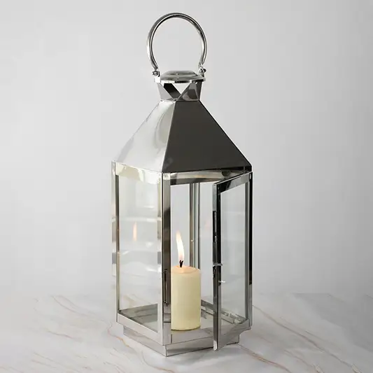 Stainless steel lantern with lit candle and glass panels displayed on white background for modern decor.