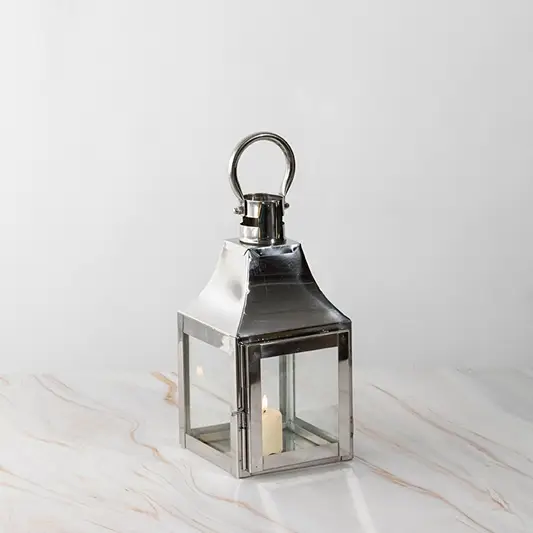 Silver lantern lit shown plain on white background highlighting polished stainless steel frame.