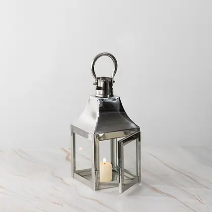 Stainless steel lantern with candle lit displayed on white background for modern home and garden decor.