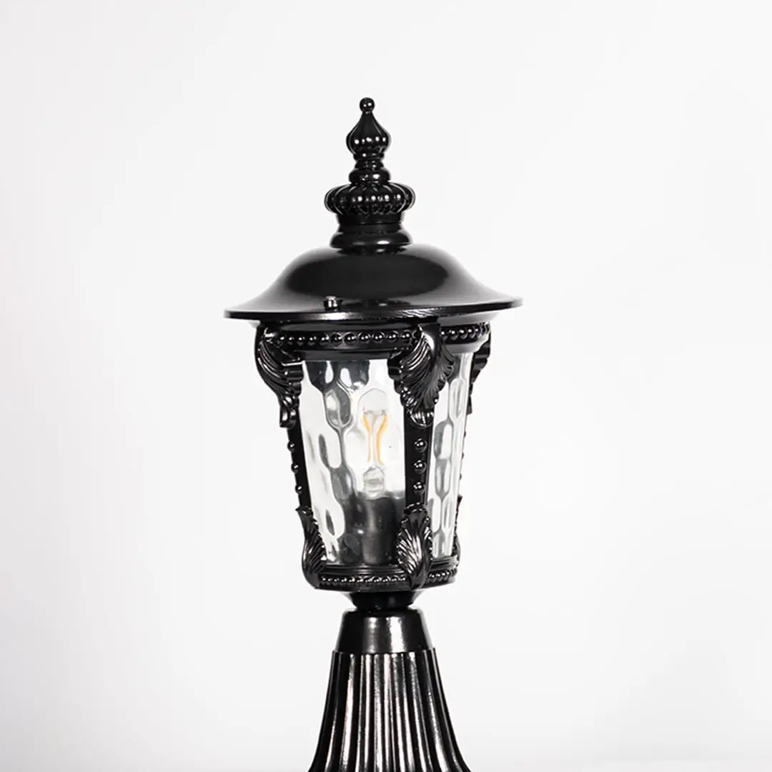 Closeup of black pillar light showing ornate frame design and patterned clear glass for stylish vintage outdoor lighting.