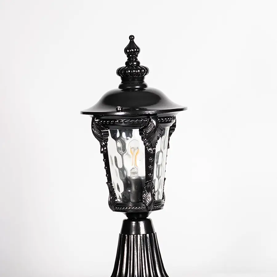 Closeup of black pillar light showing ornate frame design and patterned clear glass for stylish vintage outdoor lighting.