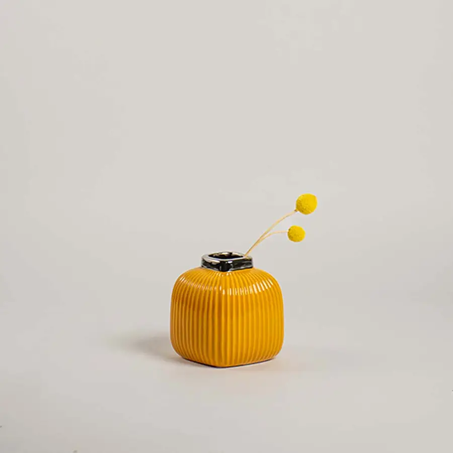 Modern yellow ceramic vase with ribbed texture displayed on a simple white background highlighting its bright finish.