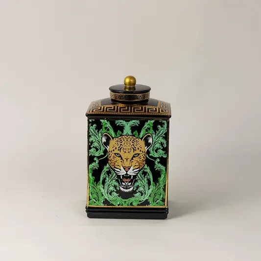 Black ceramic jar against white backdrop emphasizing glossy finish and vivid gold-green detailing.