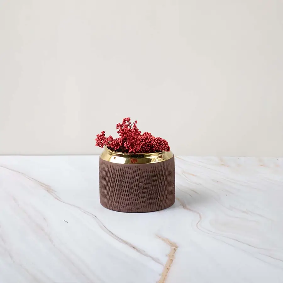A low brown vase with a gold rim placed on a soft marble background showing a refined stylish look perfect for enhancing modern interiors.