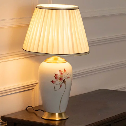 Floral ceramic table lamp with pleated fabric shade offering warm traditional lighting and elegant home decor appeal.