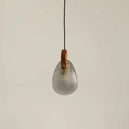 Smoke glass pendant light with gold metal fixture illuminated to showcase elegant modern ceiling lighting appeal.