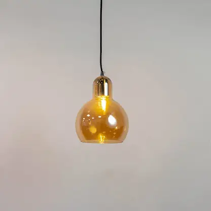 Amber glass and brass metal pendant light with warm glow for elegant contemporary home decor spaces.