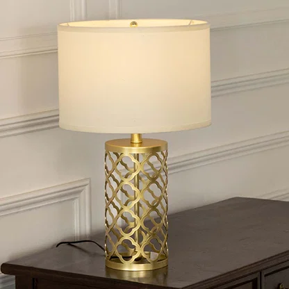 Gold lattice metal table lamp with fabric shade offering sophisticated decorative lighting for modern luxury interiors.