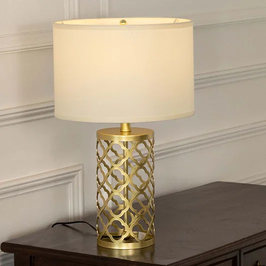 Gold lattice metal table lamp with fabric shade offering sophisticated decorative lighting for modern luxury interiors.