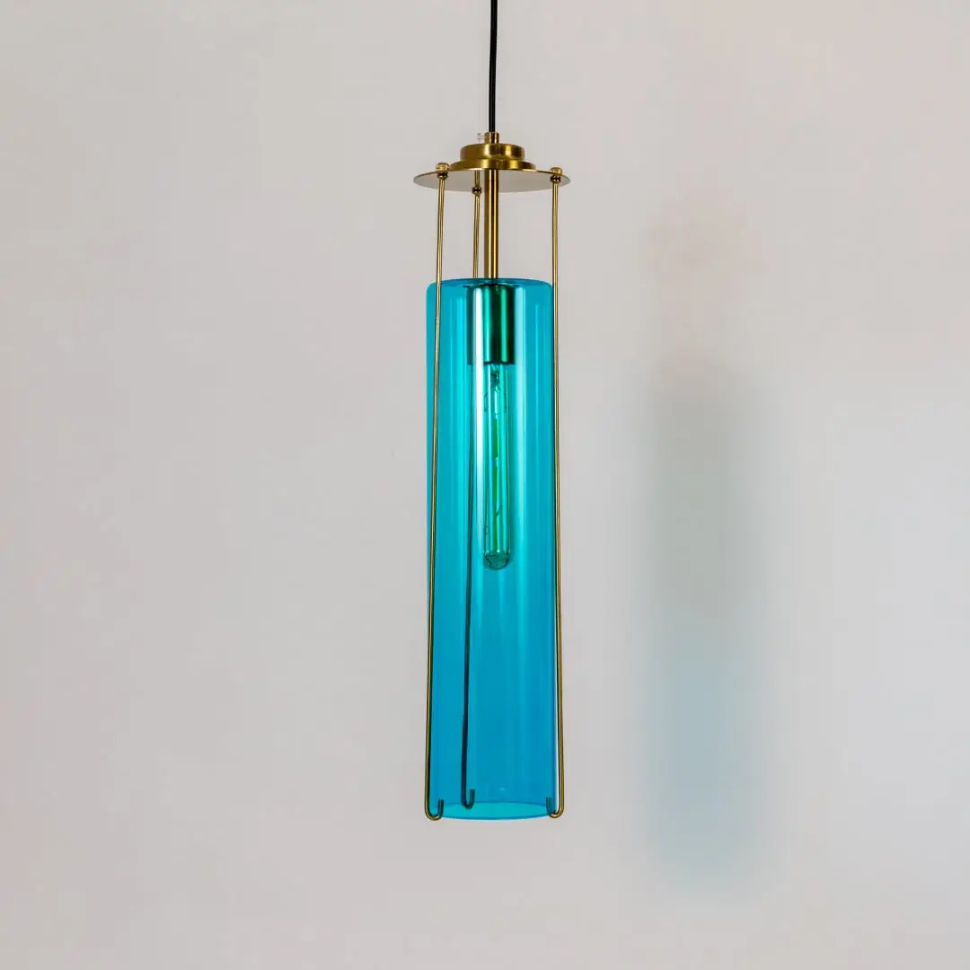 Blue glass pendant light with gold metal fixture illuminated to showcase luxury decorative ceiling lighting.