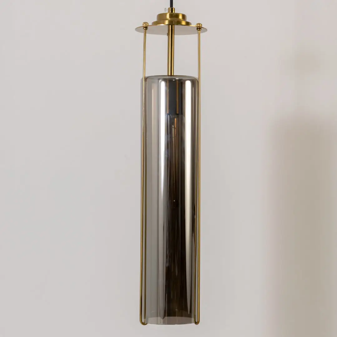 Closeup pendant light in gold metal finish with cylindrical glass shade for kitchen or dining decor lighting white background.