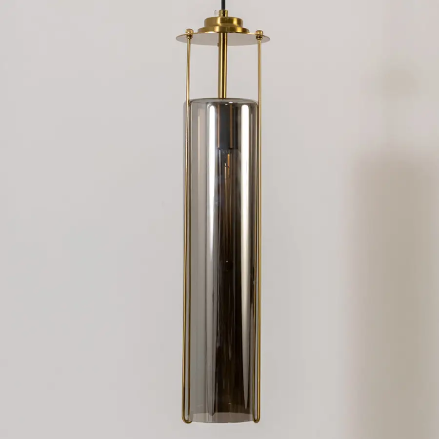 Closeup pendant light in gold metal finish with cylindrical glass shade for kitchen or dining decor lighting white background.